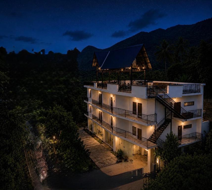 a large white building with a balcony at night at Rivendell resort Munnar in Munnar