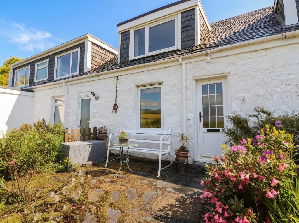 a white house with a bench in front of it at 4 Whiterow in Appin
