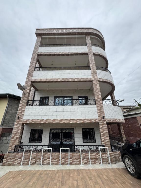 a tall building with windows and a car parked in front at L Arche in Douala