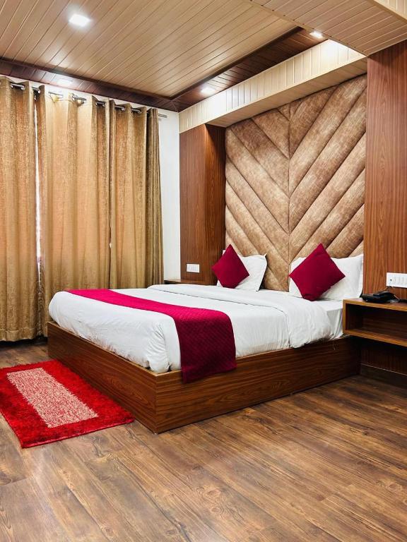 a bedroom with a large bed with red pillows at YogMaya Regency in Shimla