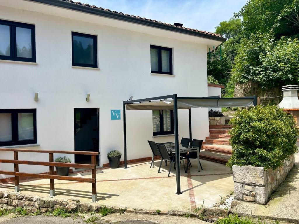 a patio with a table and chairs in front of a house at Casa El Acebal in Llanes