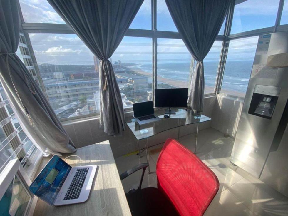 a room with a desk with a laptop and a red chair at Beach Apartment in Durban in Amanzimtoti