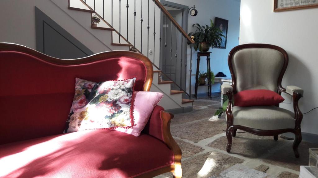 sala de estar con sofá rojo y silla en casa rural la Perla, en Hiendelaencina