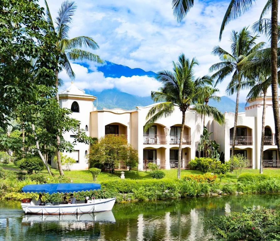 a resort with two boats in the water and palm trees at Promisedland Resort & Lagoon in Shoufeng