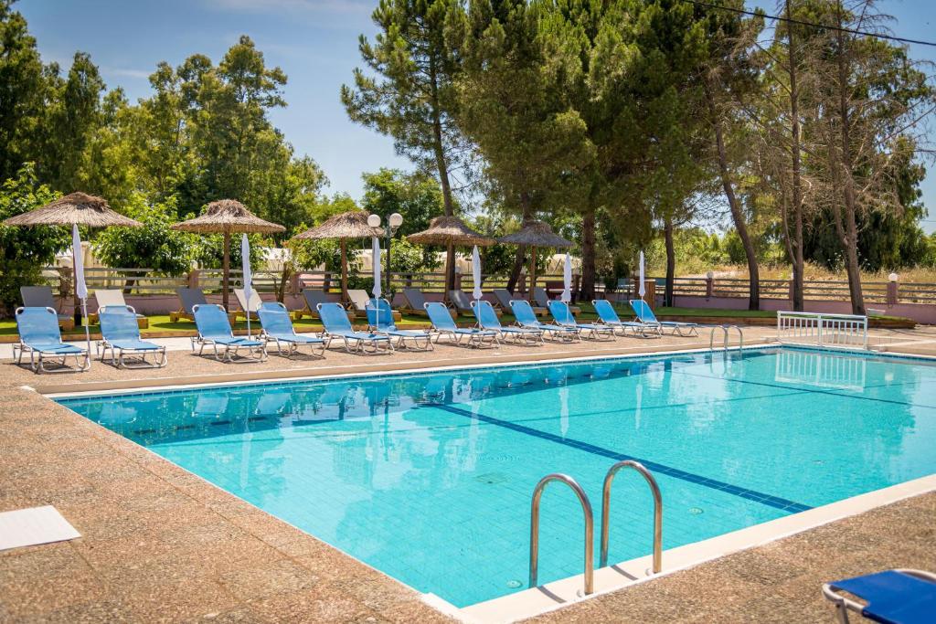 a swimming pool with chairs and umbrellas at Apollo Hotel in Laganas