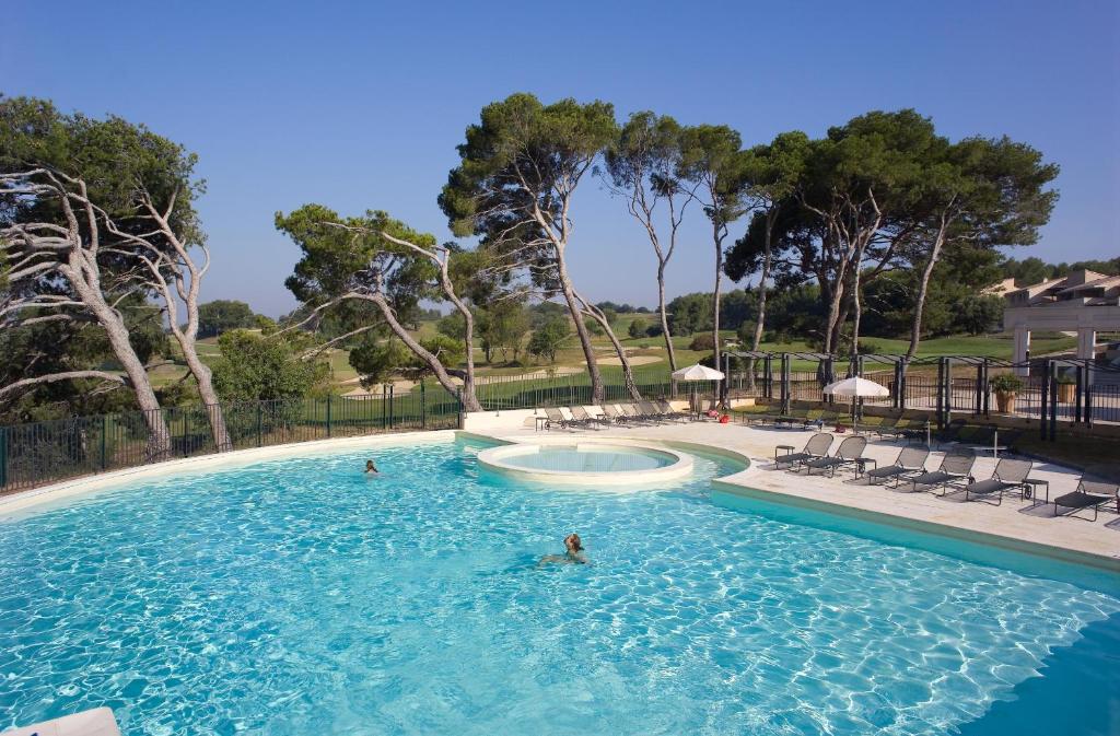 - une piscine avec 2 personnes dans l'eau dans l'établissement Madame Vacances Résidence Provence Country Club, à Saumane-de-Vaucluse
