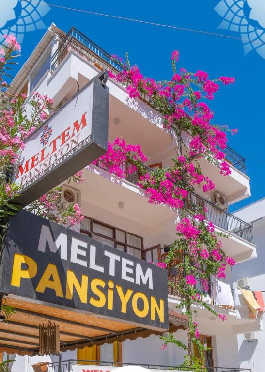 a building with pink flowers and a sign on it at meltem pansiyon in Kaş
