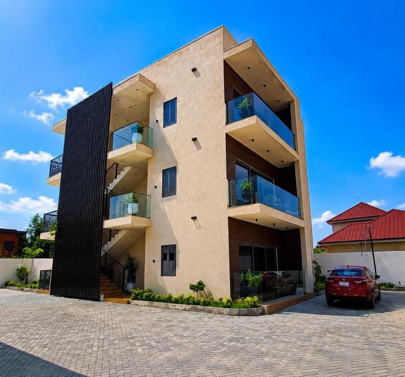 a building with a red car parked in front of it at Luxury Balcony Apartment at THE HIDDEN DOMUS I Prestige Apartment in Accra