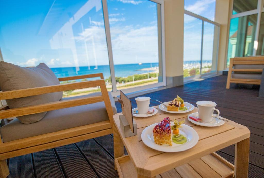 two plates of food on a table with a view of the ocean at Morada Strandhotel Ostseebad Kühlungsborn in Kühlungsborn