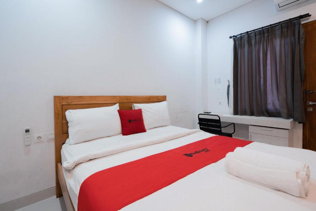 a bedroom with a large bed with a red blanket at RedDoorz Plus at Kencana Residence Jimbaran in Jimbaran