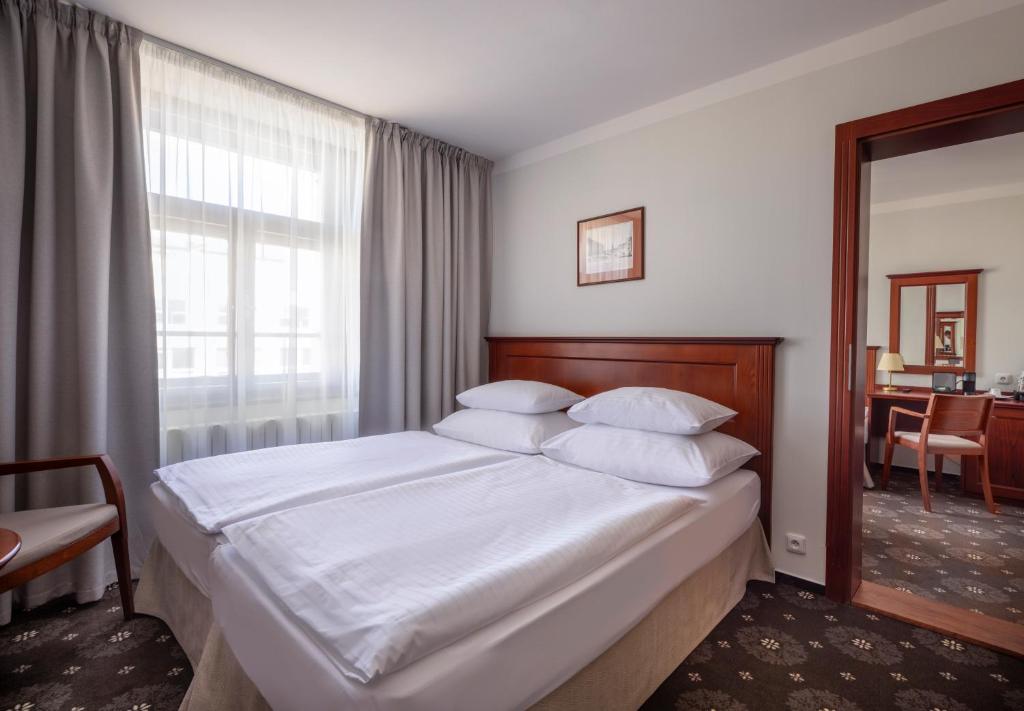 a bedroom with a bed with white sheets and a window at Hotel Lunik in Prague