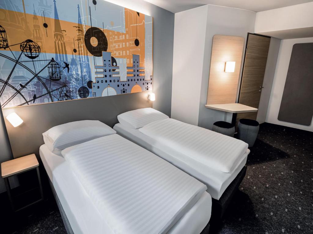a room with two beds and a painting on the wall at B&B HOTEL Wien-Heiligenstadt in Vienna
