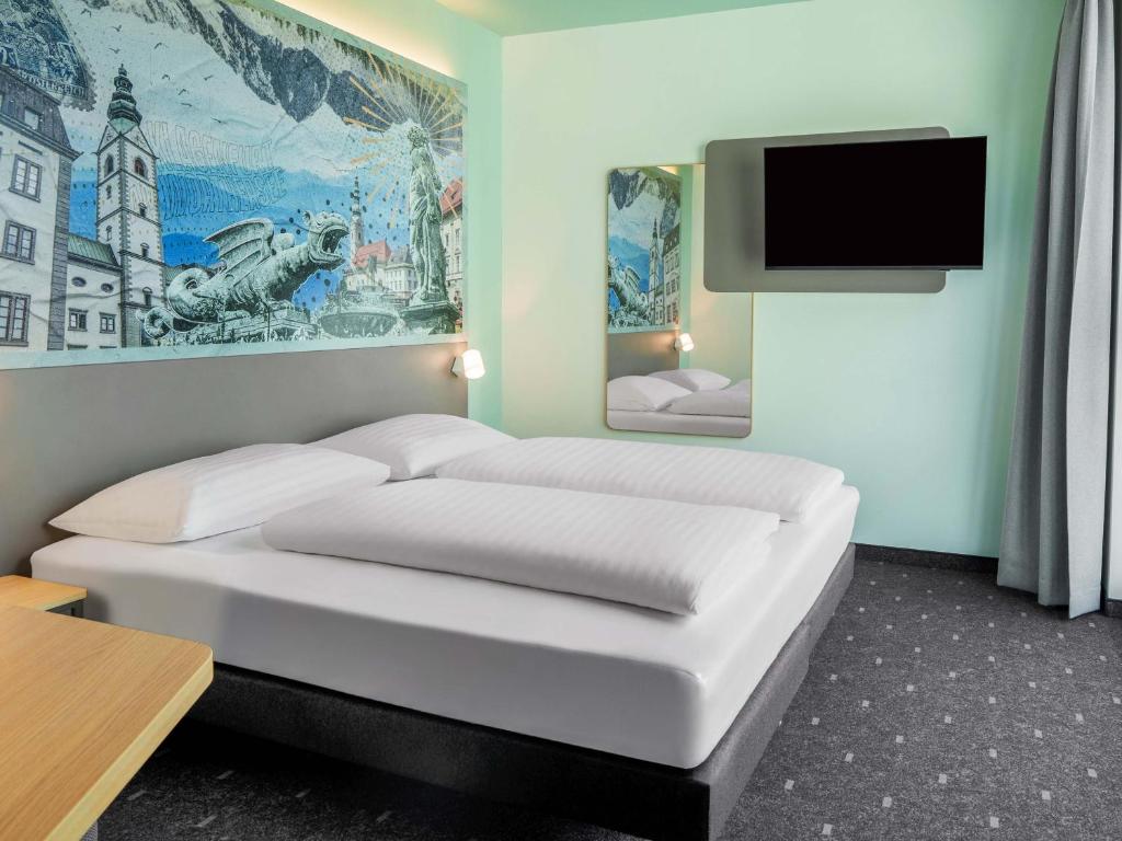 a room with two beds and a flat screen tv at B&B HOTEL Klagenfurt-City in Klagenfurt