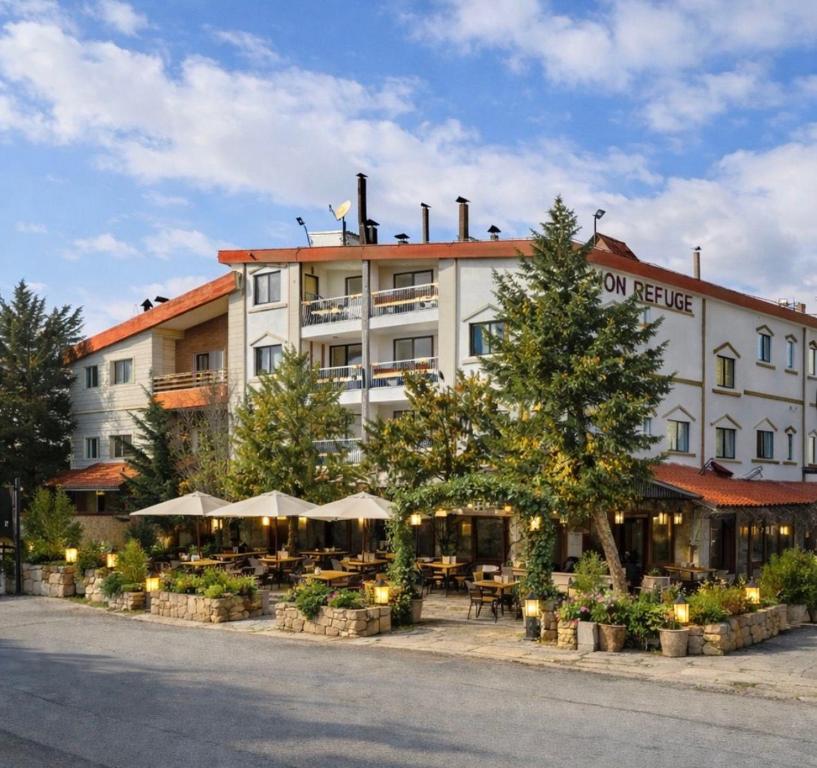 a hotel with tables and umbrellas in front of it at Mon Refuge 123 in Bcharré
