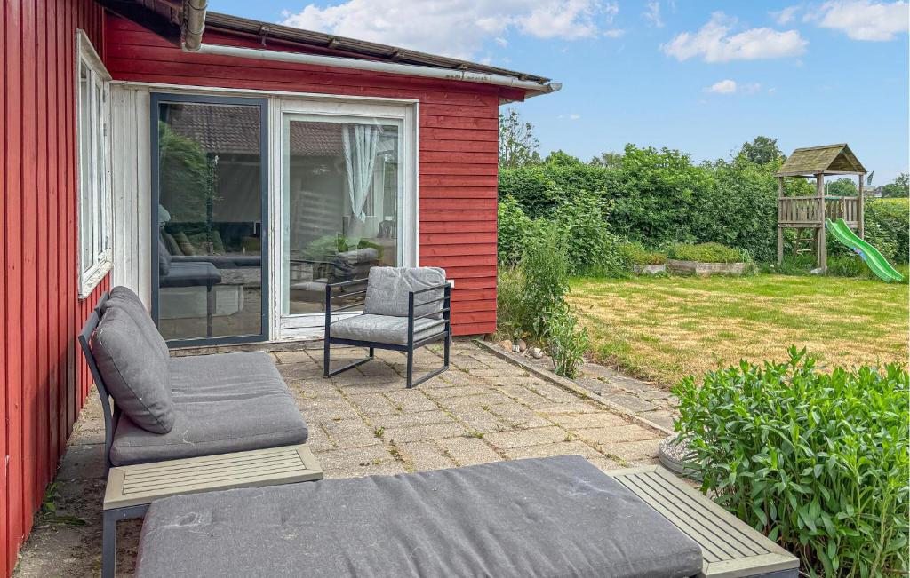 a red house with a patio with a couch and a chair at 2 Bedroom Pet Friendly Home In Haderslev in Haderslev