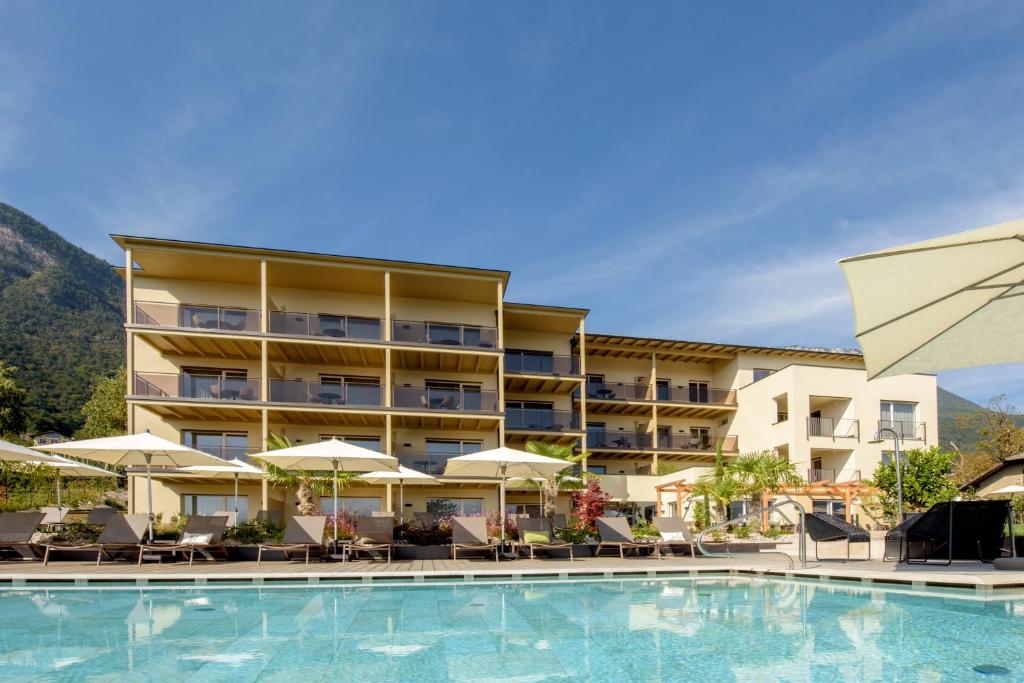un hôtel avec une piscine dotée de chaises et de parasols dans l'établissement Brühl Suites&Residence, à Caldaro