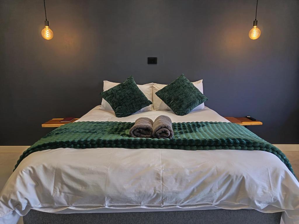 a bed with a green blanket and two slippers on it at Unit 8 Dinas Accommodation Oranjemund in Oranjemund