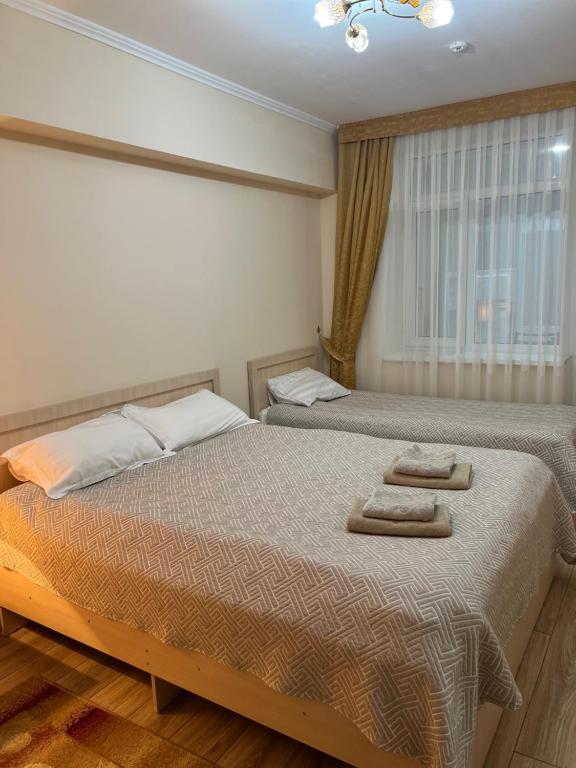two beds in a bedroom with two towels on them at АпартаментРадугаВест1 in Koshkolʼ