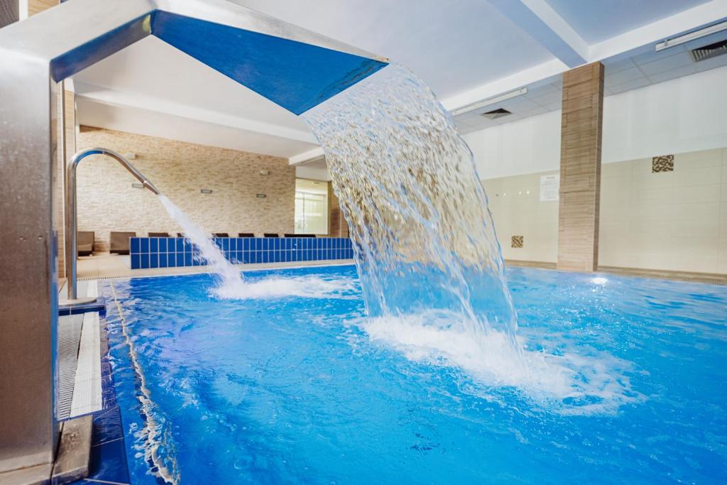 ein Schwimmbecken mit einem Springbrunnen in einem Gebäude in der Unterkunft Instytut Zdrowia Sofra FIT & SPA in Karpacz