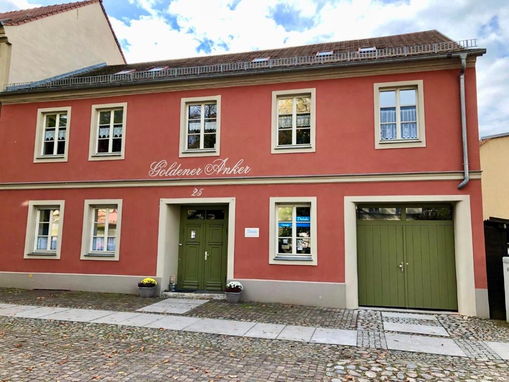 a red house with green doors on a street at Goldener Anker, verschiedene gemütliche Ferienwohnungen in Rheinsberg