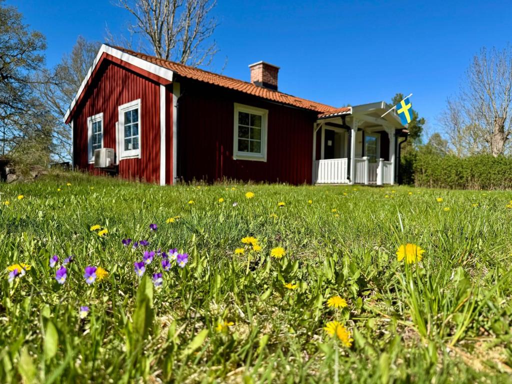 a red house with a field of flowers in front of it at Haus Sommerlycka in Fågelfors