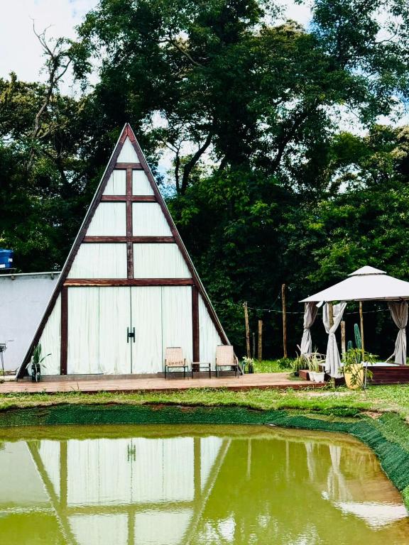 a barn with a table and a tent next to a pond at Chalé Paraíso in Nerópolis