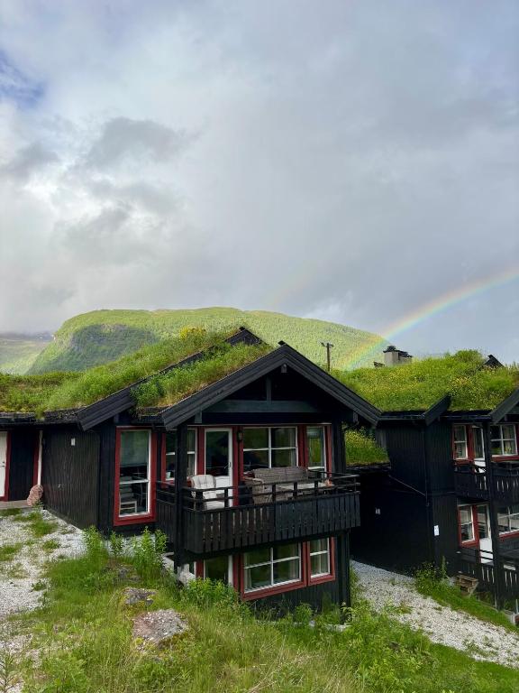 a house with a grass roof with a rainbow in the background at Apartment vårstølen - myrkdalen skisenter in Vossevangen
