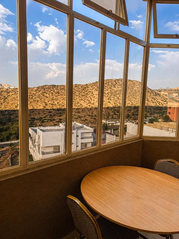 a table and chairs in a room with a large window at البساتين هومز - Al Basateen Homes in Al Baha