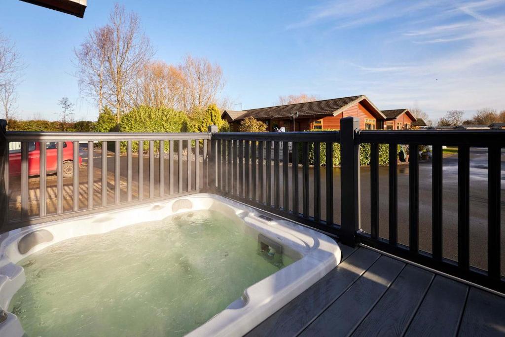 a hot tub on a deck with a fence at Penny Lodge with Hot Tub in Malton