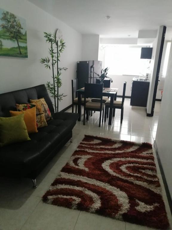 a living room with a black couch and a table at Aptos hermosos en sector turistico in Montenegro