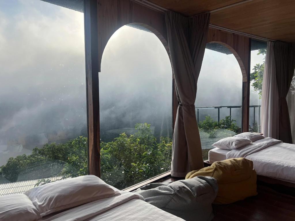 two beds in a room with a large window at Mimoza homestay cầu đất in Xuân Trường