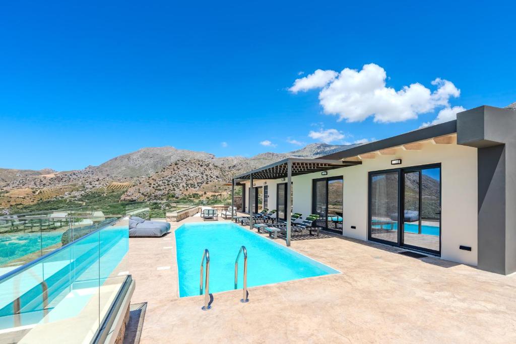a house with a swimming pool with mountains in the background at Rodia Luxury Villa in Plakias