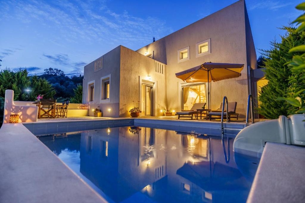 a swimming pool in front of a house at Villa Calma in Patitiri