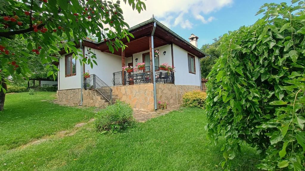 a small white house with a balcony on a yard at къща Утринна Роса in Blŭskovtsi