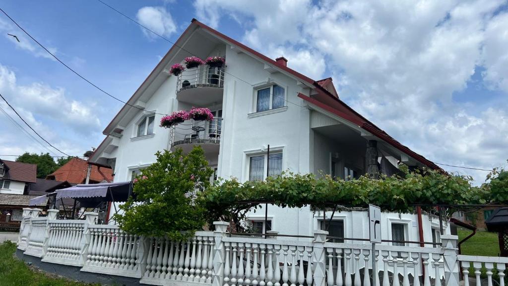 a white house with a white fence and flowers at La Bujor in Breb