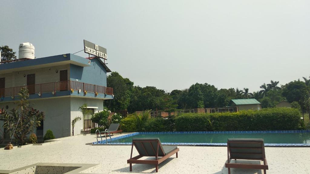 a house with two chairs next to a swimming pool at The Deerfield Cottages in Rāmnagar