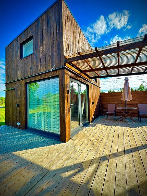 a wooden building with a deck with an umbrella at Kadaksalu with sauna hinnas in Ruu