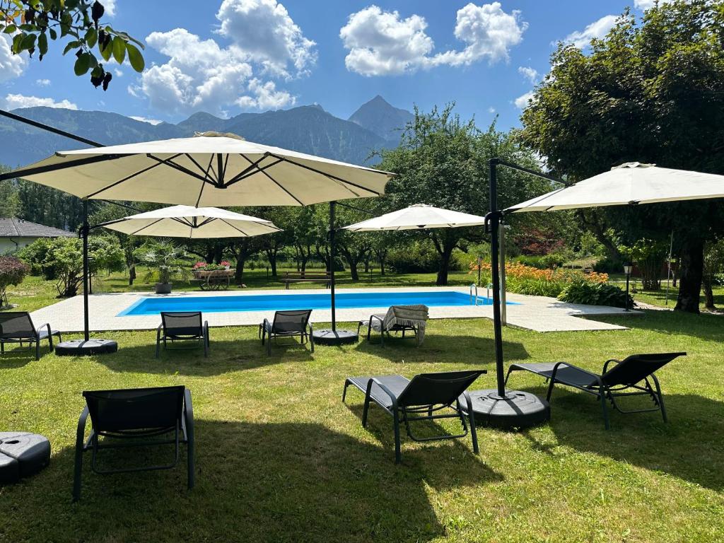 a group of chairs and umbrellas next to a pool at Hotel Kürschner in Kötschach