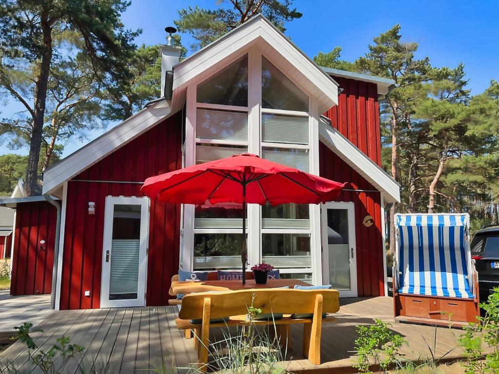a red house with a table and two chairs and an umbrella at Strandhaus Rügenperle - Baabe in Baabe