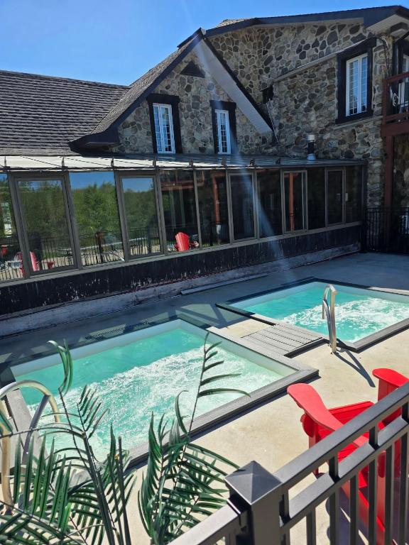 a swimming pool with red chairs and a house at Loft La Pause Orford in Magog-Orford