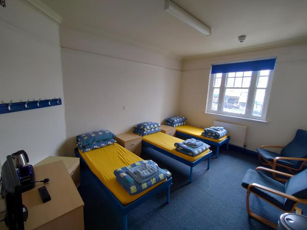 a room with three beds and chairs and a window at Adventure Bude in Bude
