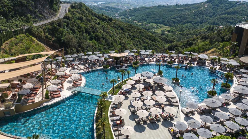 eine Luftaufnahme eines Resorts mit einem Pool mit Sonnenschirmen in der Unterkunft Select Hill Resort in Tirana