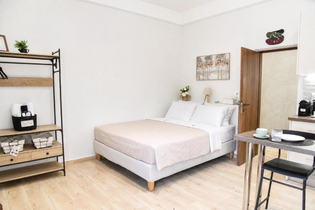 a white bedroom with a bed and a table at Nook Athens Airport in Spata