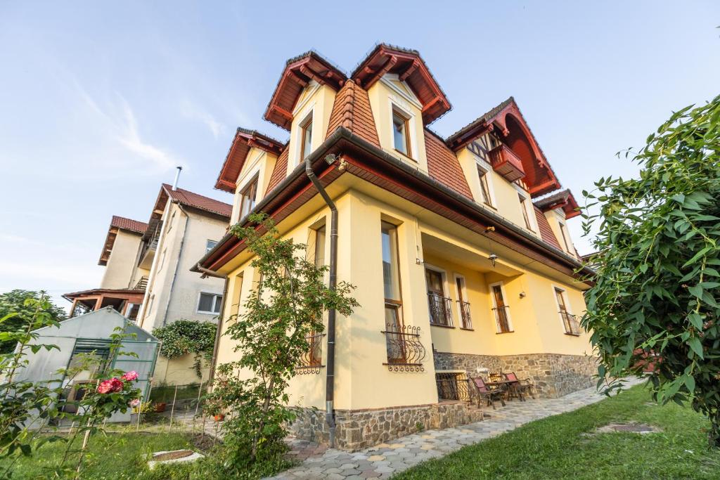 a large yellow house with a brown roof at Cherry Tree Sibiu in Sibiu