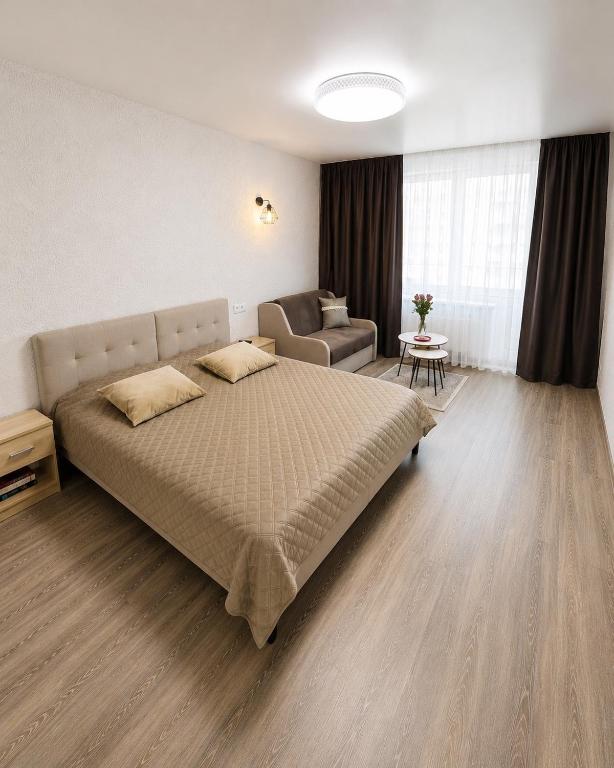 a bedroom with a large bed and a couch at Taikos apartamentas in Mažeikiai