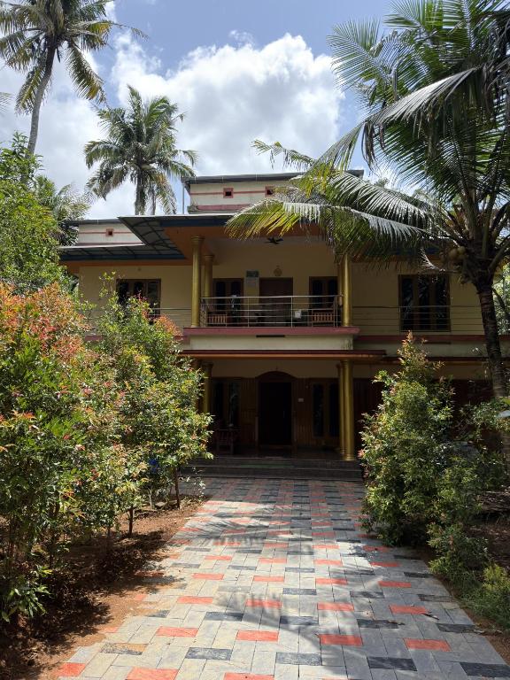 a yellow house with palm trees and a driveway at Hayath Homes in Athirappilly