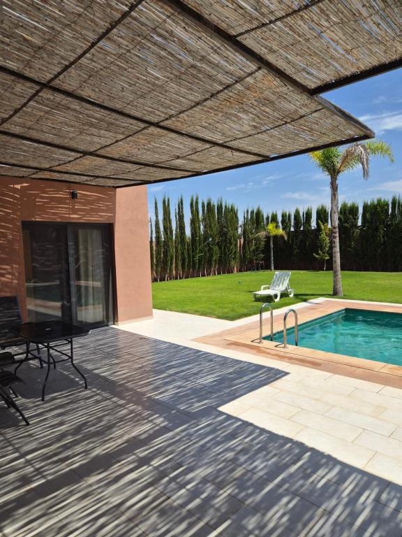 a patio with a table and chairs and a swimming pool at Agadir sans vis a vis in Bouria