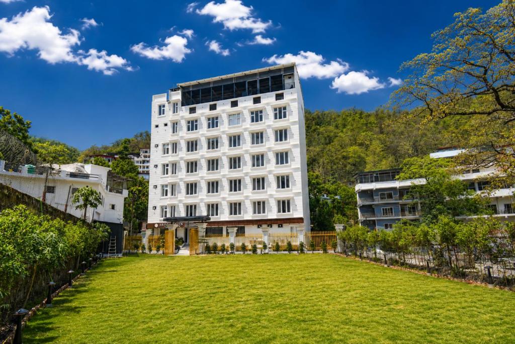 a white building with a lawn in front of it at Arista Haven Hotel in Rishīkesh
