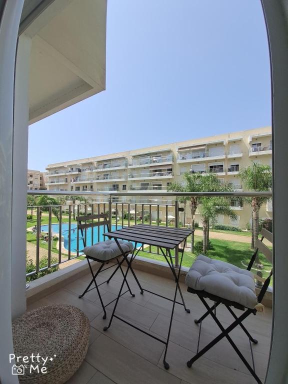 a balcony with a table and chairs and a building at Chaleureux appartement in Bouznika