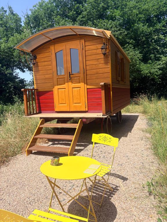 a tiny house on a trailer with a table and chairs at La roulotte de Clemence in Montfermy